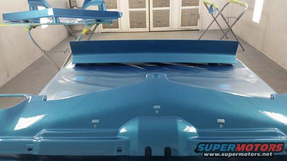 Blue car hood and spoiler in paint booth