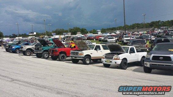 White Ford Bronco with hood open, parked in a lot with other trucks