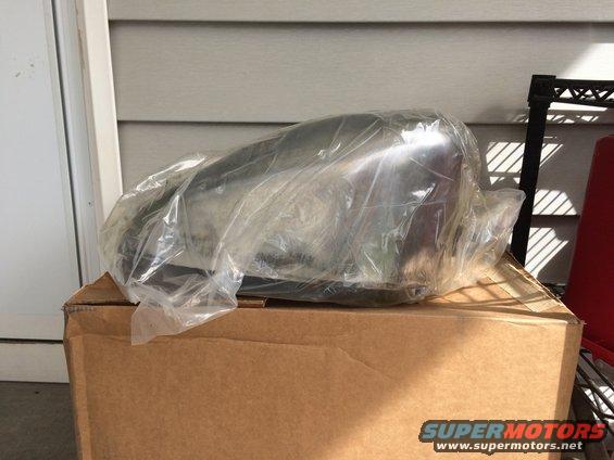 Chrome motorcycle exhaust pipe in plastic wrap on a cardboard box