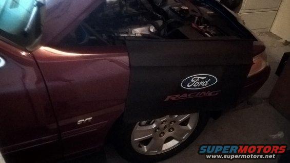 Maroon car fender with Ford Racing cover and wheel