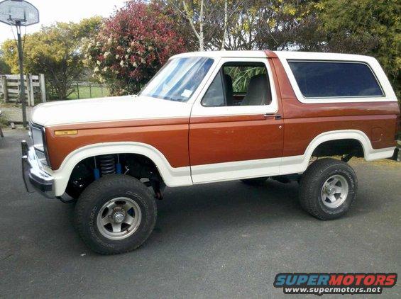 Two-tone brown and white Ford Bronco with lifted suspension and aftermarket wheels