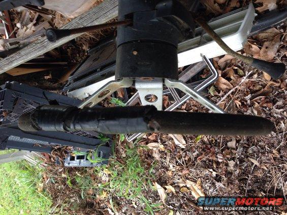Steering column assembly with black tape, surrounded by debris and car parts