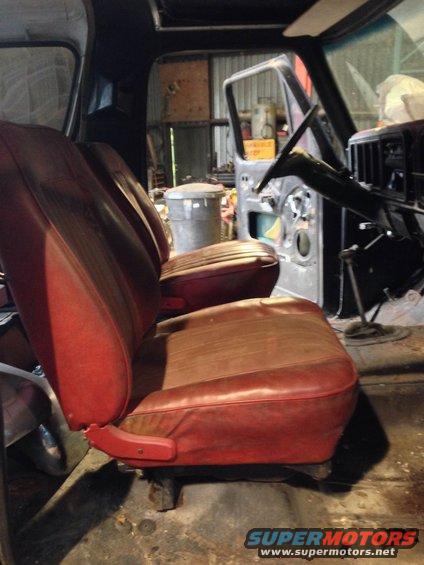 Red bucket seats inside a disassembled vehicle, showing the steering wheel and open door
