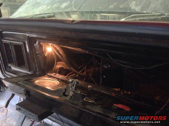 Open glove box showing wiring and a light bulb inside a car's dashboard