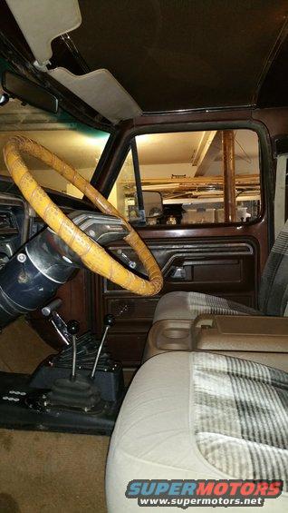 Interior view of vintage vehicle with yellow steering wheel, plaid seats, and dual shifters