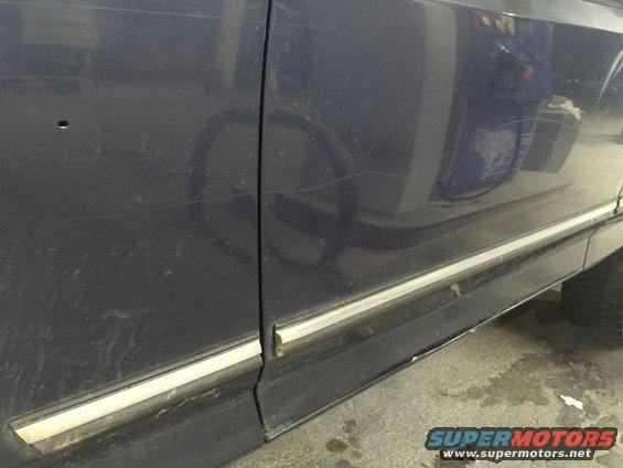 Dark blue vehicle side panel with chrome trim and visible scratches