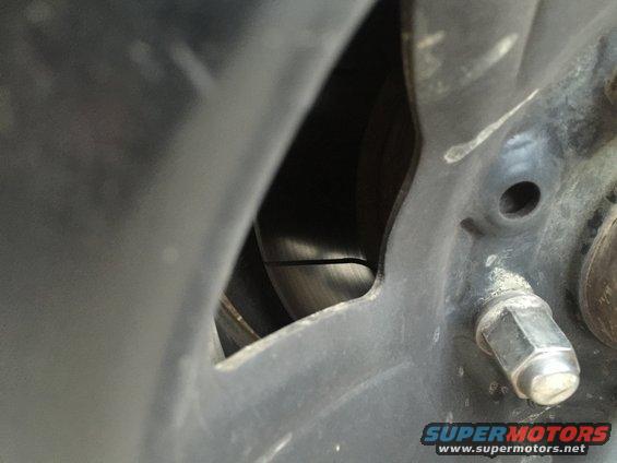 Wheel hub with lug nuts and brake rotor visible through a gap in the wheel