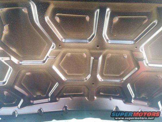 Underside of a car hood showing stamped metal reinforcement