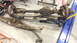 1984 Ford Bronco - Front axle and leaf springs removed from a vehicle, resting on a shop floor.