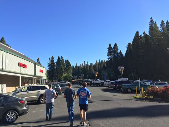 Parking lot with a gray sedan, a tan SUV, and several trucks under a clear blue sky