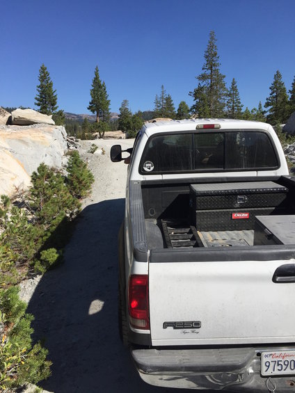 White pickup truck rear view with toolbox in bed. F250 Super Duty badging visible