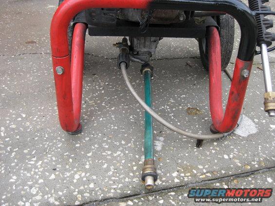 pressure washer pump with red frame and green hose connected to water inlet
