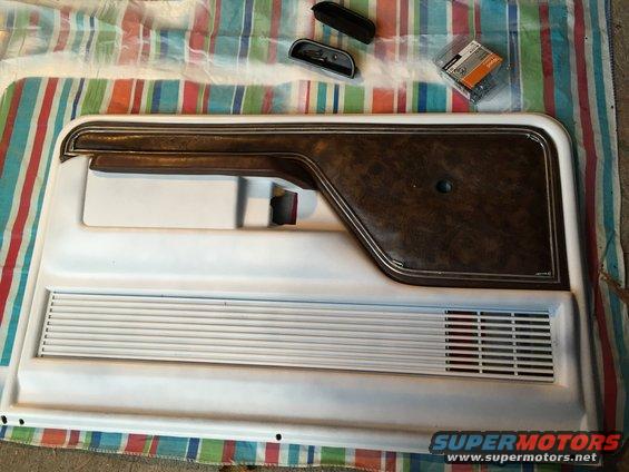 Car door panel with brown textured insert and horizontal vents, plus some loose parts and screws
