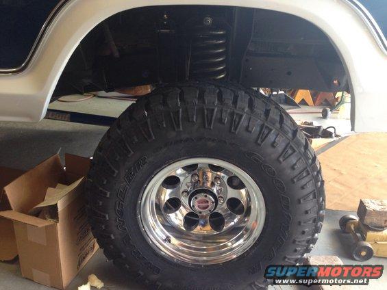 1978 Ford Bronco wheel and suspension, chrome rim, off-road tire, white fender, blue body, in garage