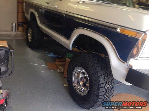 Front fender and wheel of a 1978 Ford Bronco, white with blue trim