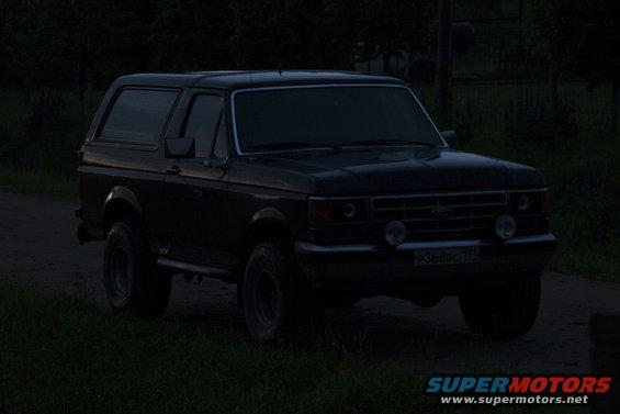 Dark 1987 Ford Bronco parked on a dirt road at dusk
