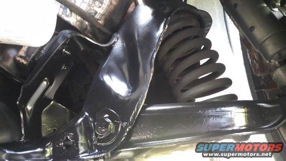 Black painted suspension arm and coil spring, viewed from below