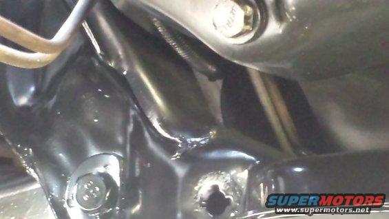 Close-up of black painted vehicle frame with bolts and suspension parts visible