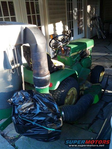 Green John Deere lawn tractor with a black bagger attachment and flexible hose