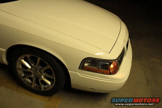 Front corner of a white 2000 Mercury Grand Marquis with chrome wheels
