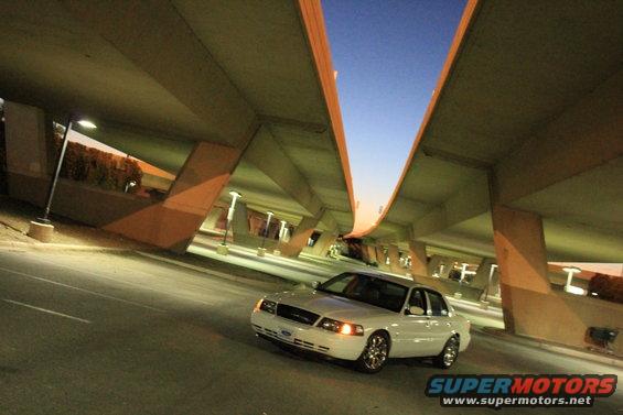 White 2000 Mercury Grand Marquis sedan, front 3/4 view, under an overpass at dusk