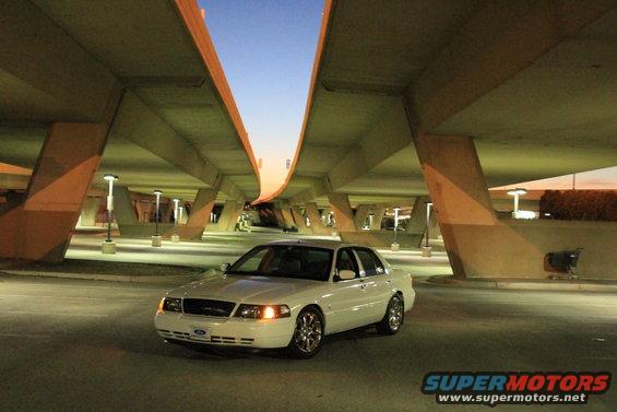 White 2000 Mercury Grand Marquis parked under a concrete overpass at dusk