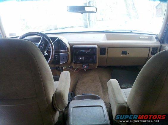 1990 Ford Bronco interior showing tan seats, dashboard, steering wheel, and center console