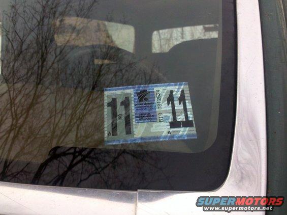 Close-up of a Pennsylvania inspection sticker on a car windshield. The sticker shows the number 11
