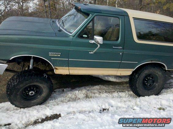 Green 1990 Ford Bronco with tan trim and lifted suspension parked in snow