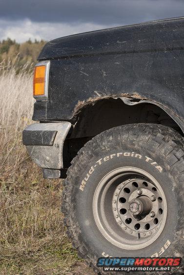 Black SUV fender with rust and a BFGoodrich Mud-Terrain T/A tire. The vehicle is seen from the front quarter