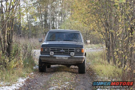 Ford Bronco parked on a dirt road with trees on either side