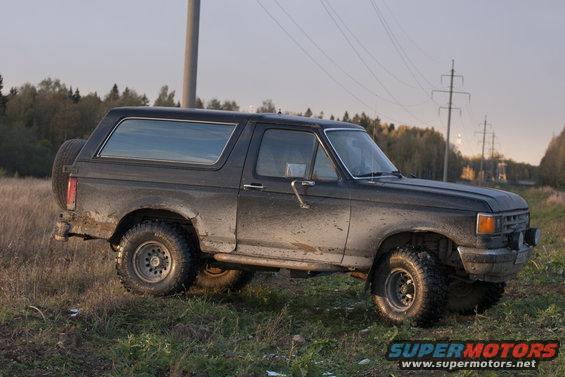 1987 Ford Bronco, dark gray, muddy, side view with spare tire on rear