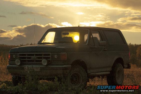 SUV parked in a field at sunset