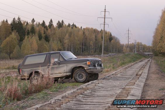 Pickup truck parked on a dirt road next to trees with fall colors