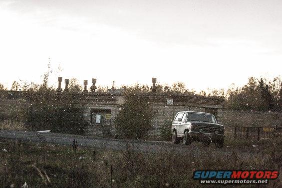 White SUV parked in a dry, brushy landscape under an overcast sky