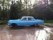1964 Mercury Comet - A blue sedan with chrome trim is parked outside on a wet driveway with trees in the background.