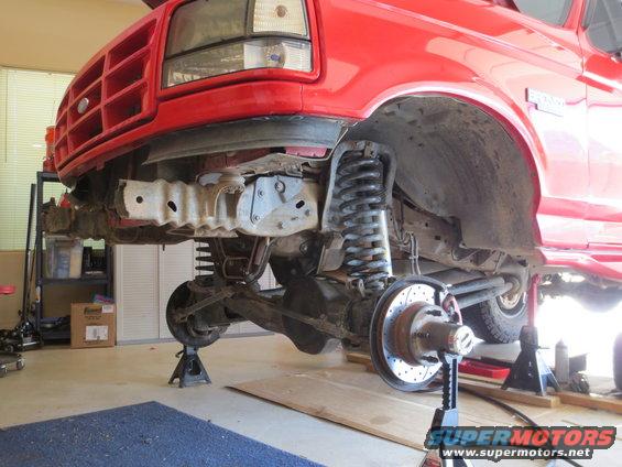 Red 1996 Ford Bronco front suspension disassembled on jack stands