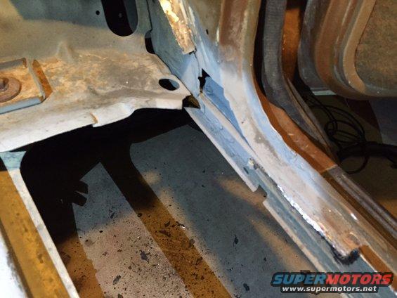 Close-up of rusted metal on a vehicle's floor pan and frame, showing damage