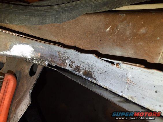 Close-up of rusted metal frame with visible welds and some grey primer