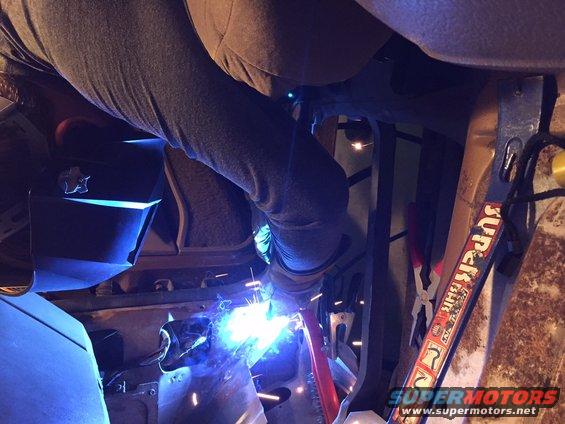 Welder sparks fly as a person repairs the rusted floor pan of a vehicle interior