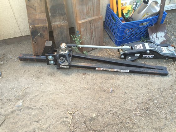 Gooseneck trailer hitch assembly with a jack and some lumber in the background