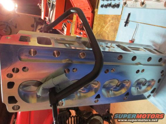 Engine cylinder head with valve seats visible, held by a clamp