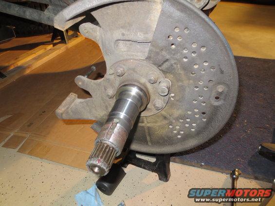 close-up of a vehicle's wheel hub assembly with brake rotor, supported by a jack stand