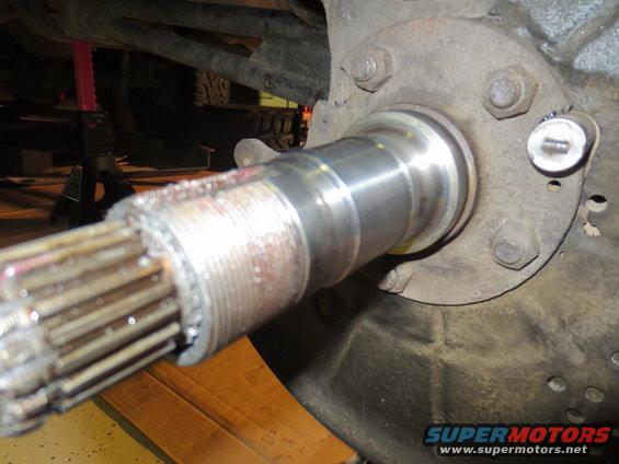 Splined axle shaft and hub assembly with metal shavings, on a jack stand