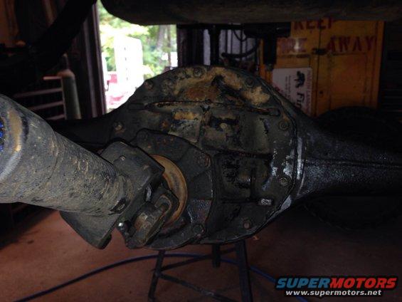 close-up of a rear axle differential with driveshaft attached, in a garage setting