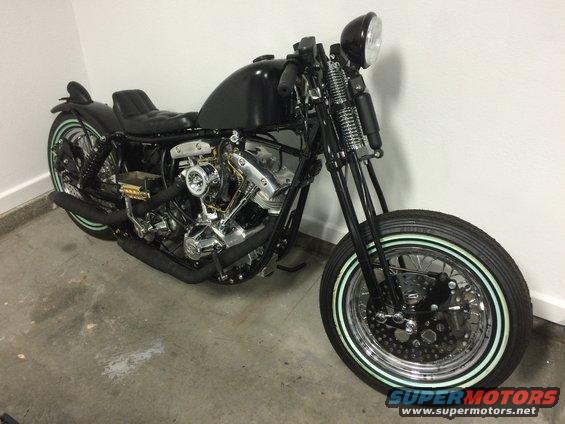 Custom black motorcycle with whitewall tires and exposed engine