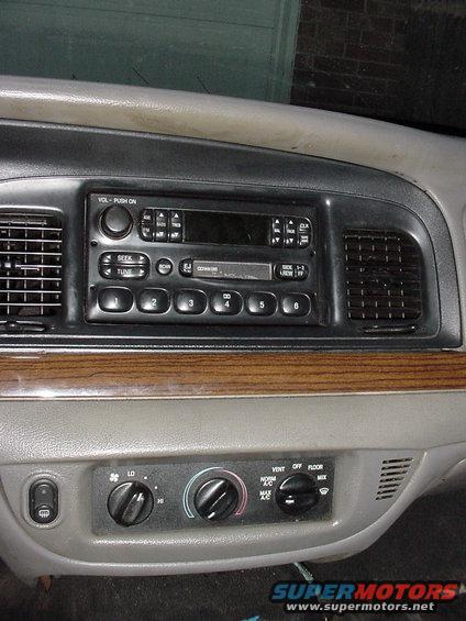 Car dashboard with radio, climate controls, and wood trim