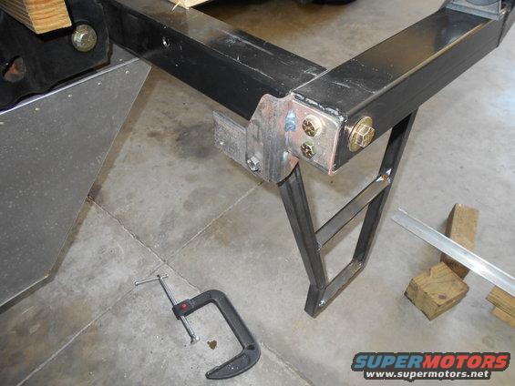 welded metal frame with bolts and a c-clamp on concrete floor