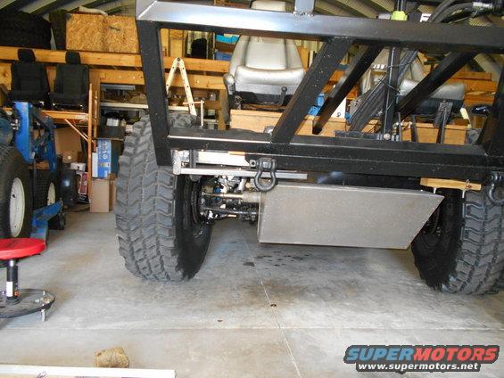 Custom off-road vehicle chassis with large tires and suspension components visible in a garage
