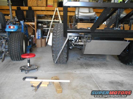 Vehicle frame with large tires, metal fuel tank, and seats in a garage